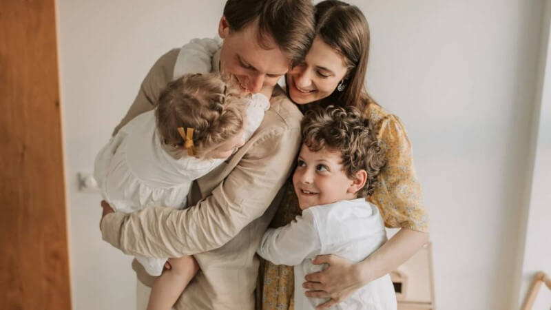 笑顔で抱き合う父と母と娘と息子の家族